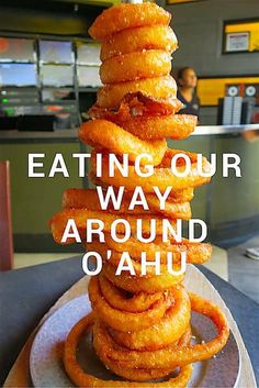 a stack of doughnuts sitting on top of a plate with the words eating our way around o'ahu