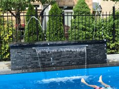 a woman swimming in a pool with a waterfall coming out of the side of it