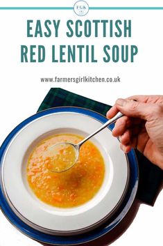 a person is holding a spoon over a bowl of red lentil soup on a blue and white plate