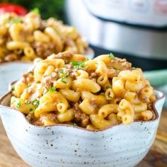 two bowls filled with macaroni and cheese on a cutting board next to an instant pressure cooker