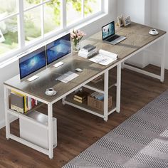 a computer desk with two monitors and a laptop on it in front of a window