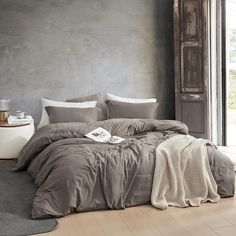 a large bed sitting next to a window in a room with gray walls and wooden floors