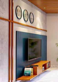 there is a television on the wall in this living room with three clocks above it