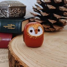 an owl figurine sitting on top of a piece of wood next to books