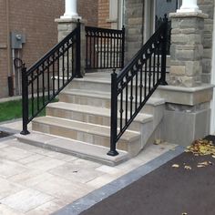 a black wrought iron stair railing next to a brick building with white pillars and windows