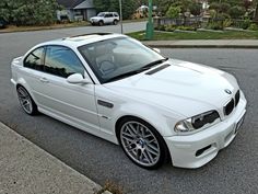 a white bmw is parked on the side of the road