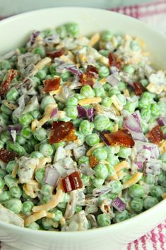 a white bowl filled with peas, bacon and other toppings on top of a red and white table cloth