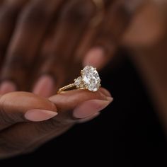 a close up of a person's hand holding a ring with a diamond on it