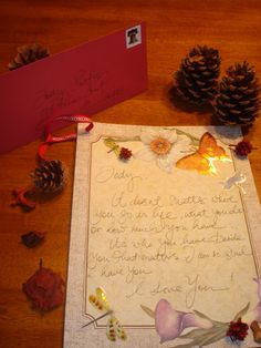 a piece of paper with writing on it next to some pine cones and other decorations