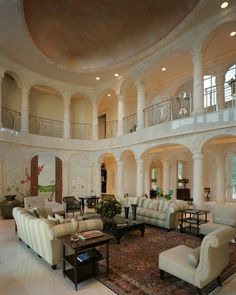 a large living room with two couches and chairs in front of a spiral staircase