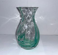 a green glass vase sitting on top of a white table