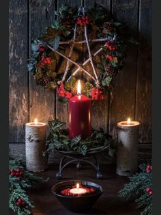 a candle and some holly wreaths on a table