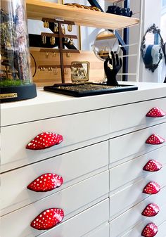 a white dresser with red polka dot knobs on it's handles and drawers