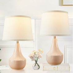 two lamps sitting on top of a table next to a vase with flowers in it