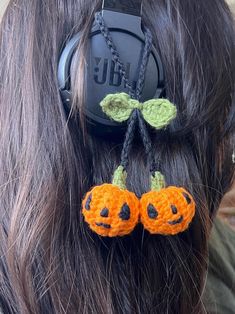 a woman with headphones on her ears has two crocheted pumpkin headsets attached to her hair