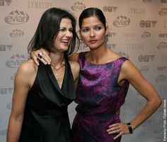 two women standing next to each other in front of a red carpeted wall with the words live tv on it