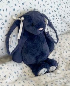 a blue stuffed animal sitting on top of a bed covered in white and blue sheets