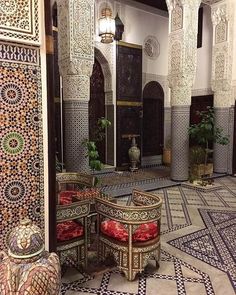 the interior of an ornately decorated building with red and white chairs, potted plants and decorative tiles