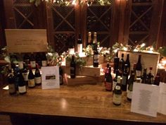 several bottles of wine sitting on top of a wooden table next to cards and lights