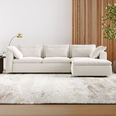 a white couch sitting on top of a wooden floor next to a table and lamp