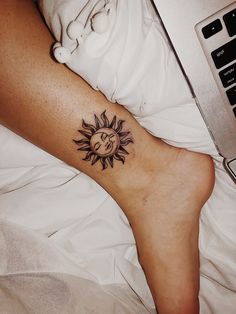 a woman's foot with a sun tattoo on it