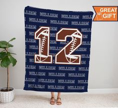 a football themed blanket with the number twenty two on it in brown and blue, next to a potted plant