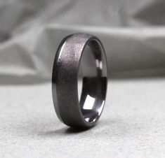 a wedding ring with a black ceramic inlay is shown on a white tablecloth