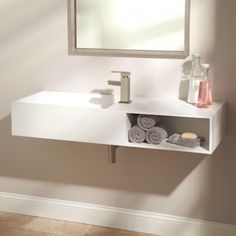 a bathroom sink sitting under a mirror next to a wall mounted soap dispenser