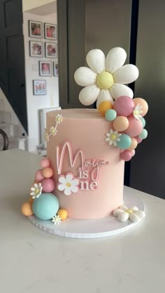 a pink cake decorated with flowers and balloons