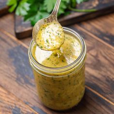 a spoon full of pesto sauce on top of a wooden table