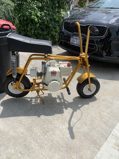 a small yellow motorcycle parked next to a black car