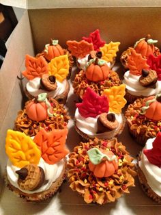 a box filled with lots of cupcakes covered in frosting and decorated like leaves