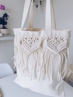 a white bag with tassels hanging from it's side on a table