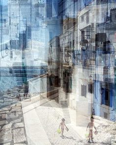 two children are playing on the beach in front of an old building with balconies