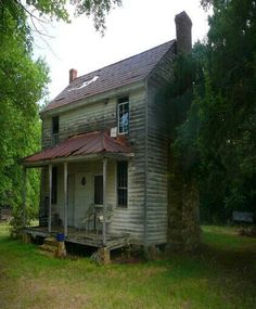 an old run down house sitting in the middle of a field with trees around it