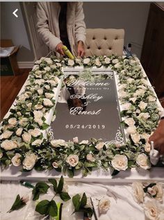 a table topped with flowers and greenery next to a sign