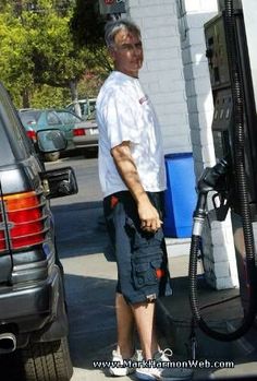 an older man pumping gas into his car