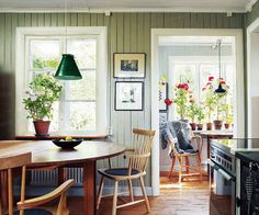 a kitchen with wooden floors and green lamps above the stove top oven in front of a dining room table