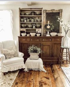 a living room filled with furniture and flowers on top of a wooden table next to a window