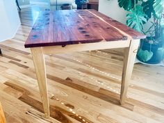 a wooden table sitting on top of a hard wood floor next to a potted plant