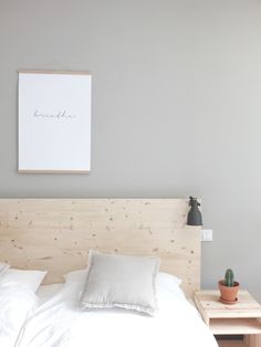 a bed with white sheets and pillows next to a wooden night stand in a bedroom