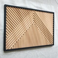 a wooden wall hanging on the side of a white wall with black trimmings