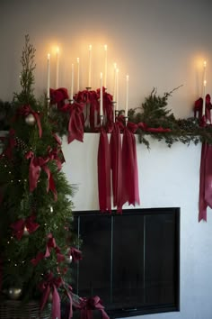 a fireplace decorated for christmas with candles and bows