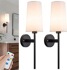 a person holding a remote control in front of two lamps and a mirror with the same light on it