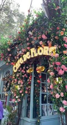 the entrance to an outdoor cafe with flowers growing on it