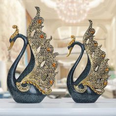 two black and gold vases sitting on top of a white table with a chandelier in the background