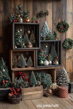 christmas trees and other decorations are arranged on wooden crates in front of a wood paneled wall