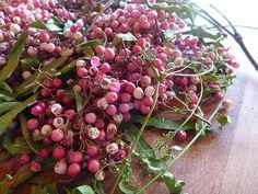 a bunch of berries that are on top of a wooden table with leaves and flowers