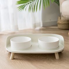 two white bowls sitting on top of a wooden tray