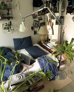 a bed with blue sheets and pillows in a bedroom next to a plant on the floor